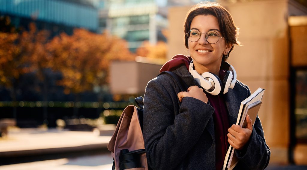 A student on a city street carrying books and a backpack