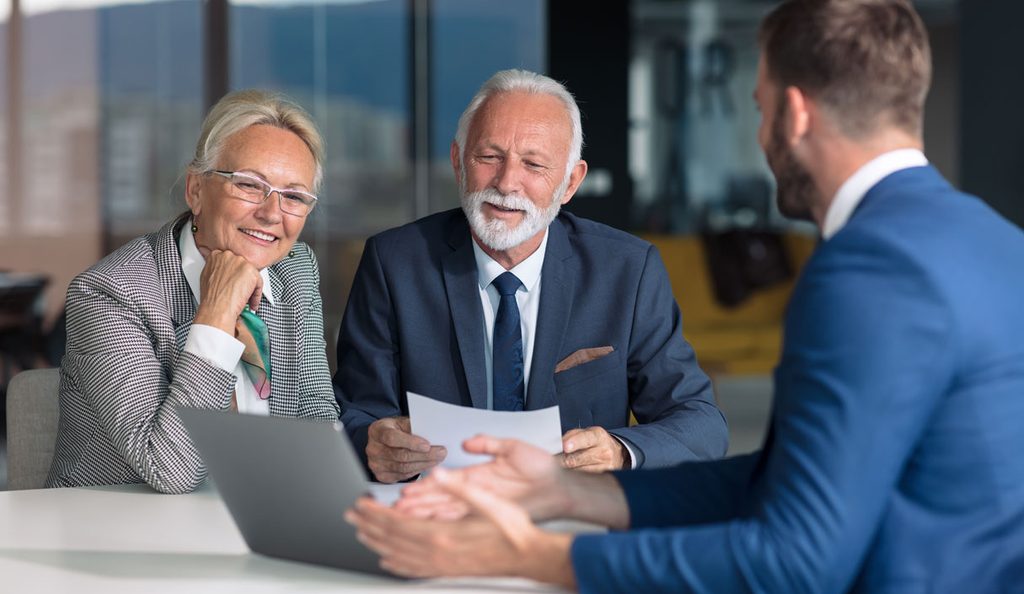 Two clients reviewing a document with an advisor across a desk