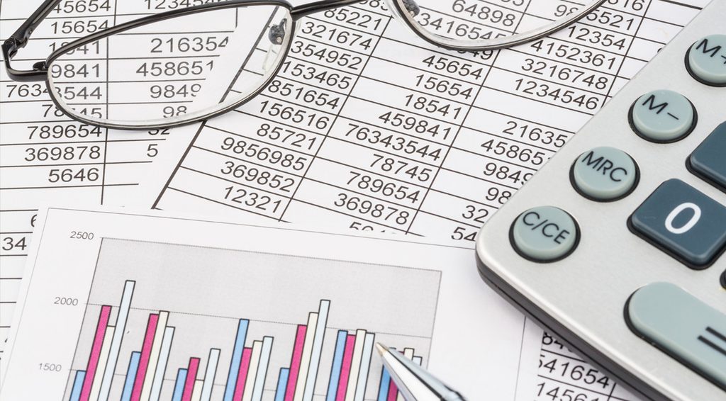 A calculator, glasses, and a bar chart on printed tax tables